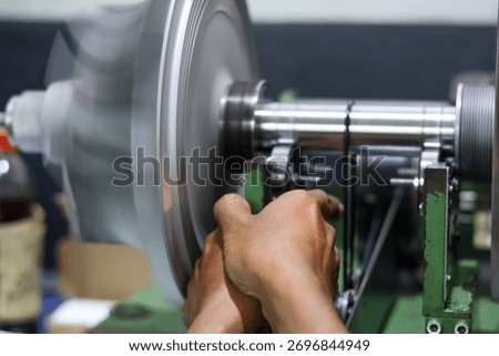 Close-up of a worker operating a dynamic balancing machine, adjusting the high-speed rotating turbine or fan component in a heavy industrial factory environment.