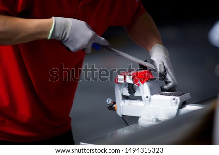 close-up of a worker in a red t-shirt processing a metal workpiece clamped in a vice