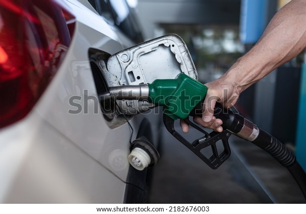 Close-up of worker standing on gas station and\
fueling car.