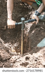 Close-up of a worker using a manual soil auger to drill the ground. Concept of soil testing, agriculture work, geotechnical survey, construction preparation, and manual labor outdoors.