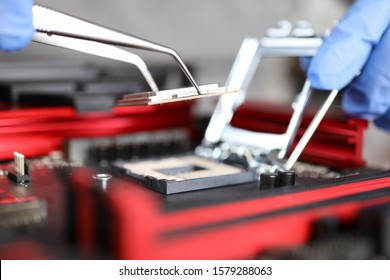 Close-up Of Workers Hands Repair Computer. Man Putting Cpu On Motherboard. Macro Shot Of Intel Microprocessor In The Socket. Upgrade And Technology Concept