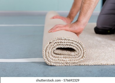 Close-up Of Worker's Hands Rolling Carpet At Home