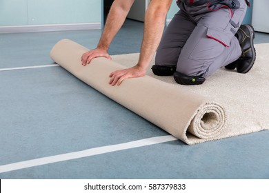 Close-up Of Worker's Hands Rolling Carpet At Home