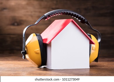 Close-up Of Working Yellow Protective Headphone On The House Model Over The Wooden Table