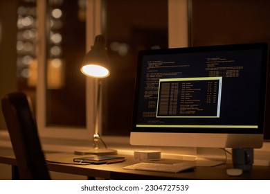 Close-up of workplace of developer with computer with security codes on monitor in dark office
