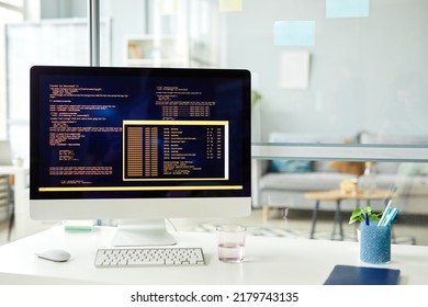 Close-up of workplace of programmer with computer standing on it with codes on monitor at office