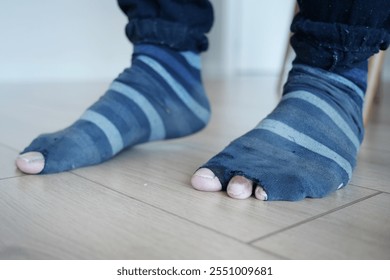 Close-Up of Worn Out Striped Socks on Wooden Floor - Powered by Shutterstock