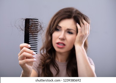 Close-up Of A Worried Woman Holding Comb Suffering From Hairloss