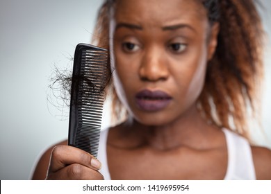 Close-up Of A Worried Woman Holding Comb Suffering From Hairloss