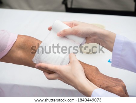 closeup wound dressing An Elderly patient. hand of doctor using bandage covering on senior woman’s arm at home, medical and healthcare concept