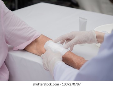 closeup wound dressing infection the An Elderly patient. a using bandage covering on senior woman’s arm. wearing clean glove to protect from spreading virus, copy-space medical healthcare concept 