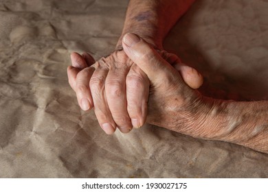 Close-up of the wrinkled hands of an elderly man, old mans hands resting on the table, paper background