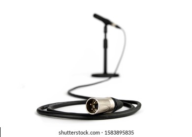 closeup of XLR audio connector on an audio cable connected to a microphone on a table stand