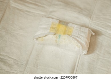 Close-up Of A Yellow Dirty Diaper Of A Newborn Baby Lying On A Baby Diaper