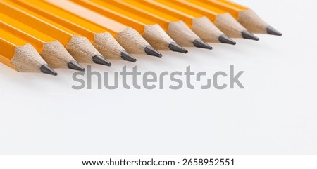 Close-up yellow graphite pencils with sharp tips lined up on a white background. Great for office use and art supplies