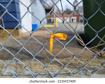 A Closeup Of A Yellow Ribbon Tied To A Fence.