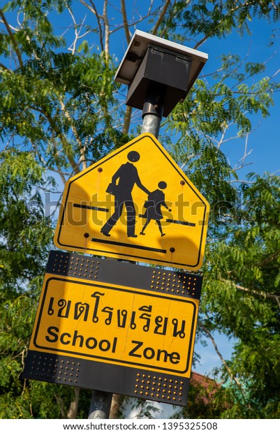 closeup of yellow school zone sign with light and\
solar cell