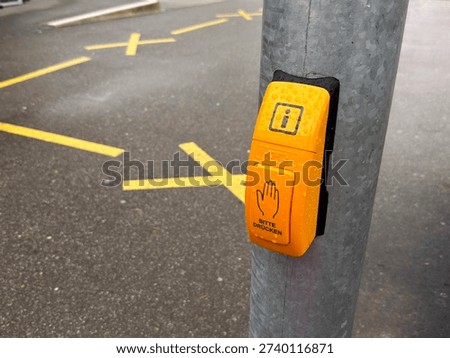 Close-up of yellow stop request button on metal pole at public transport stop.