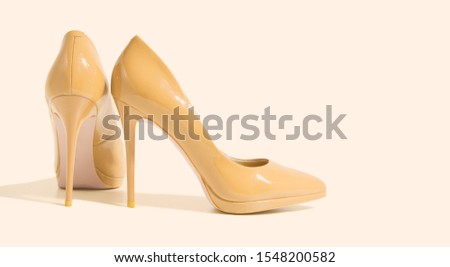 Closeup yellow women patent leather shoe isolated light background. Stilettos shoe type. Summer fashion and shopping concept. Luxury, glamour party ladies wardrobe accessory. Selective focus. Banner