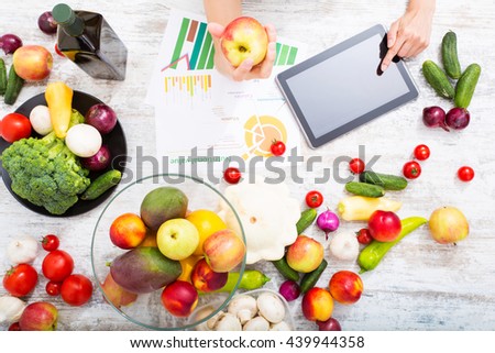 Close-up of a young adult woman informing herself with a tablet PC about nutritional values of fruits and vegetables.

