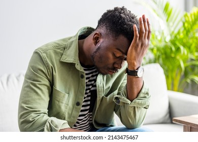 Closeup of young african american man suffering from headache at home, touching his temples, copy space, blurred background. Migraine, headache, stress, tension problem, hangover concept - Powered by Shutterstock