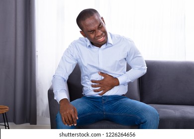 Close-up Of A Young African Man In Pain Holding His Stomach