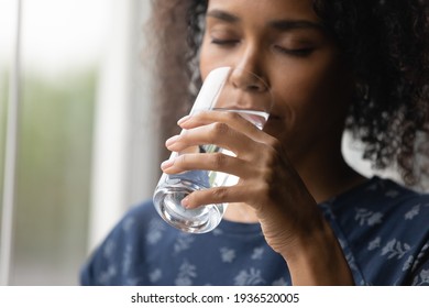 Closeup Of Young African Woman Drinking Cool Sparkling Mineral Water From Glass Hydrate Having Pleasure. Dehydrated Black Female Feel Thirsty Drink Swallow Cold Still Aqua Keep Detox Weight Loss Diet