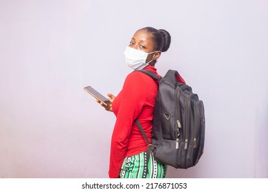 Closeup Of Young Attractive Black College Student Carrying Backpack, Holding Mobile Phone Whilst Looking At The Camera