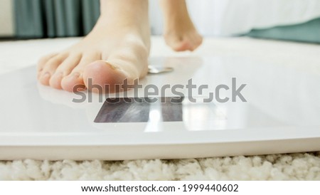 Closeup of young barefoot woman walking and standing on digital scales. Concept of dieting, loosing weight and healthy lifestyle