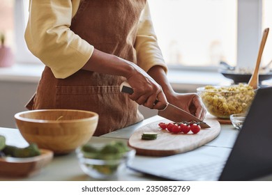 Closeup of young black woman cutting fresh vegetables while cooking with organic food in kitchen, copy space - Powered by Shutterstock