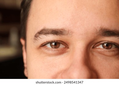 Close-up of a young brunette man with brown eyes, intense gaze. Young man with deep brown eyes.  - Powered by Shutterstock