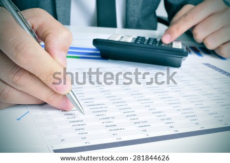 closeup of a young businessman checking accounts with a calculator in his office