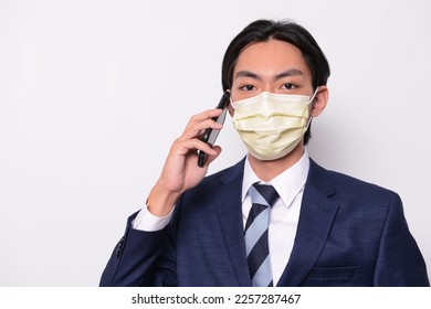 Closeup young businessman in suit wearing face mask, using smartphone. - Powered by Shutterstock