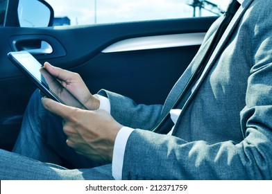 closeup of a young businessman using a tablet in a car - Powered by Shutterstock