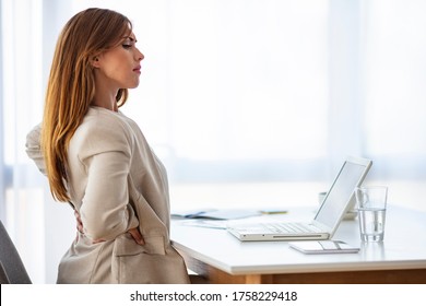 Close-up Of Young Businesswoman On Chair Having Backpain In Office. Shot Of A Young Businesswoman Experiencing Back Pain While Working In A Modern Office