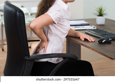 Close-up Of Young Businesswoman On Chair Having Backpain In Office