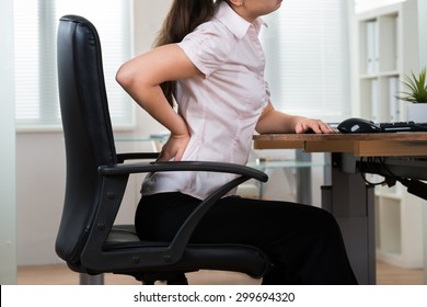 Close-up Of Young Businesswoman On Chair Having Backpain In Office