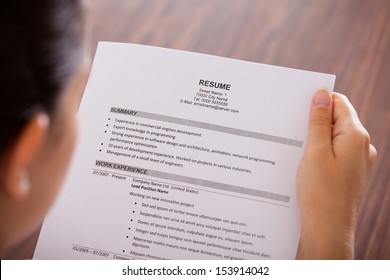 Close-up Of Young Businesswoman Reading Resume At Desk