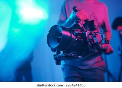 Close-up of young cameraman shooting with professional camera while making content in studio