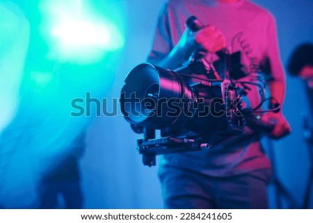 Close-up of young cameraman shooting with professional camera while making content in studio
