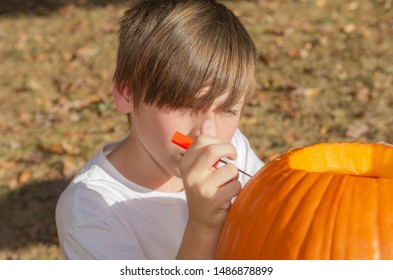 Closeup Of Young Caucasian Boy Carving Pumpkin Outside