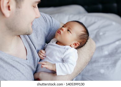 Closeup Of Young Caucasian Father With Newborn Mixed Race Asian Chinese Baby. Male Man Parent Holding Child Daughter Son. Authentic Lifestyle Touching Moment. Single Dad Family