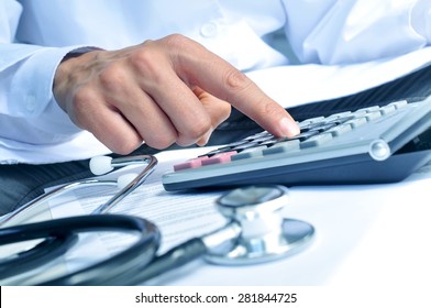 closeup of a young caucasian healthcare professional wearing a white coat calculates on an electronic calculator