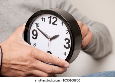 Closeup Of A Young Caucasian Man Adjusting The Time Of A Clock