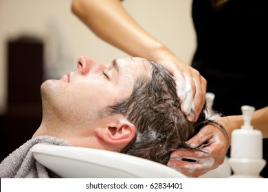 Close-up of a young caucasian man having his hair washed in a hairdressing salon - Powered by Shutterstock