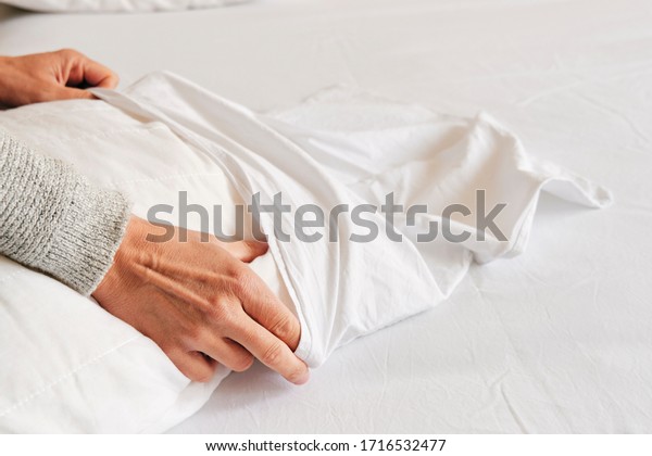 closeup of a young caucasian\
man introducing a pillow into a white pillow case as he is making\
the bed