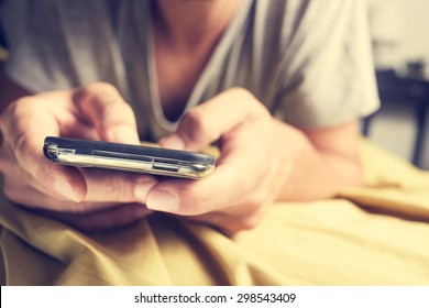 closeup of a young caucasian man in pajamas face down in bed using a smartphone - Powered by Shutterstock