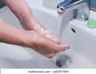 Nahaufnahme eines jungen Kaukasiers, der sich die Hände mit Seife im Waschbecken eines Badezimmers wäscht. Präventivmaßnahmen gegen Covid-19-Infektionen
