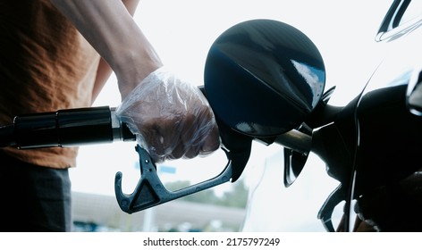 Closeup Of A Young Caucasian Man, Wearing Clear Plastic Gloves, Filling The Fuel Tank Of The Car In A Gas Station