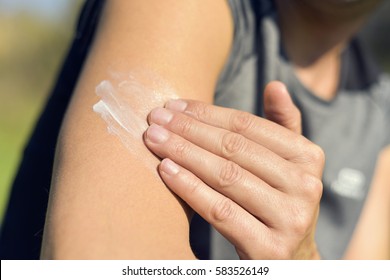 closeup of a young caucasian man wearing a T-shirt applying sunscreen to his arm
